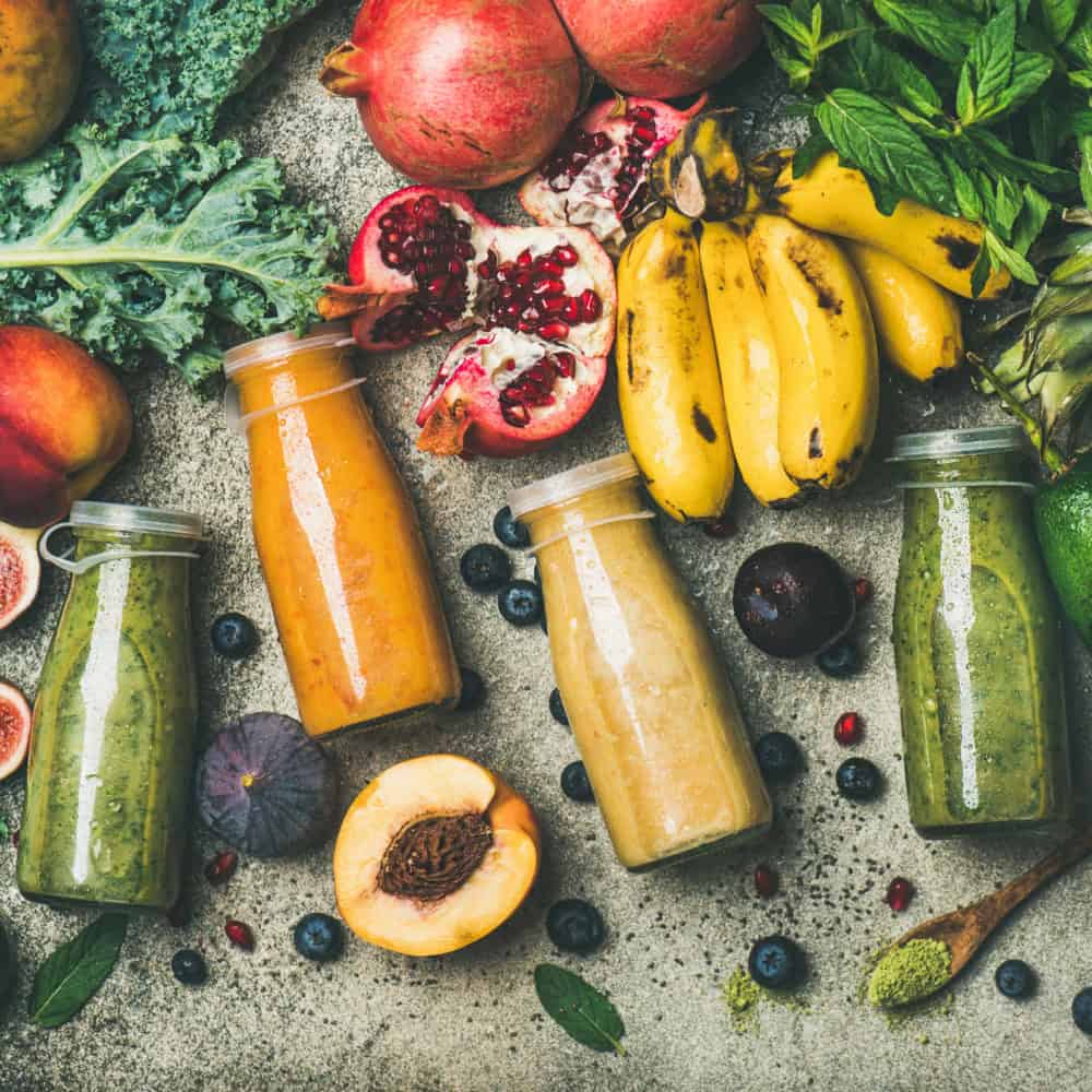 Superfoods und Smothies auf einer Granitplatte mit viel Obst und Gemüse